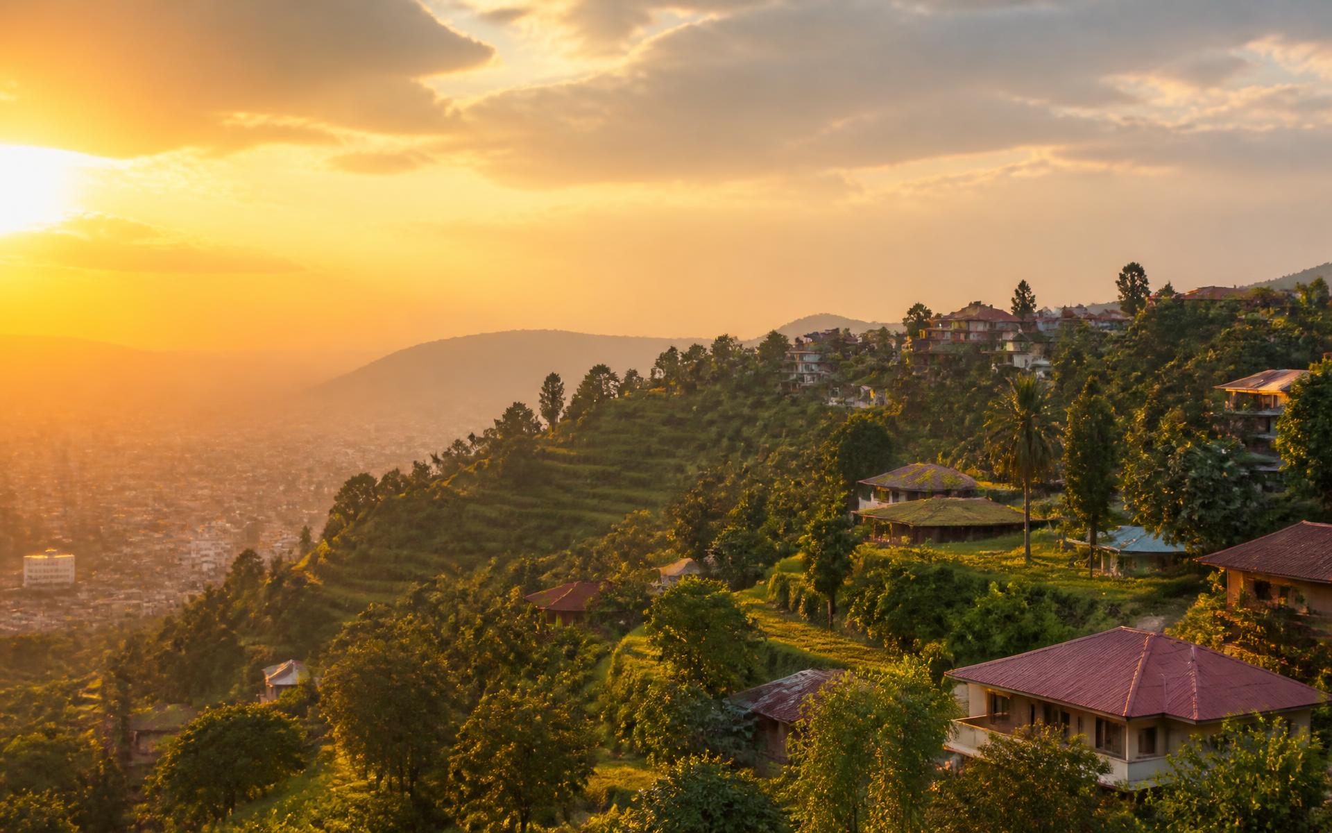 Golden-hour view over green terraced hills above an African city